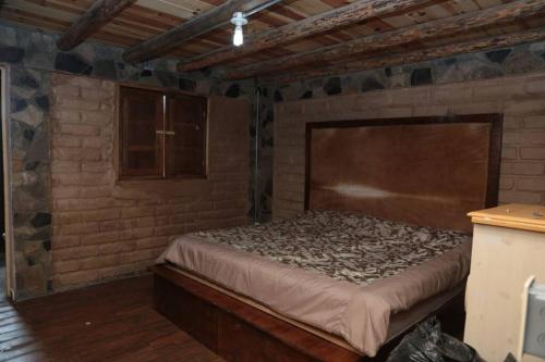 Cabaña Los Hernández في أرتياغا: غرفة نوم بسرير في جدار من الطوب