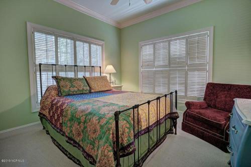 a bedroom with a bed and a chair and windows at Ingen Trafikk in Southport