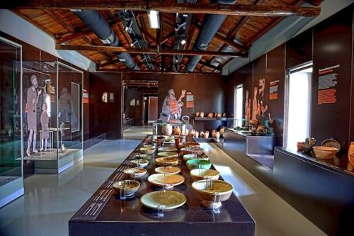 un lungo tavolo con ciotole e piatti sopra in un museo di 50 DANAIDES a Argos
