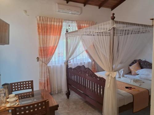 a bedroom with a canopy bed and a table at Lucky Prince Villa in Aluthgama