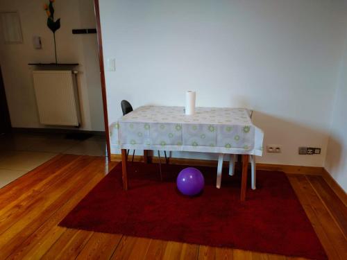 una mesa con una vela y una bola púrpura sobre una alfombra roja en Brussels Appartment en Bruselas