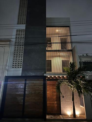 a house with wooden doors and a palm tree in front of it at CASA ALDAMA- Style & Convenient Apartments in Cancún