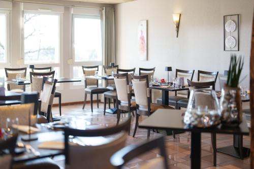 a dining room with tables and chairs and windows at Logis Hôtel Restaurant Ritter'Hoft in Morsbronn-les-Bains