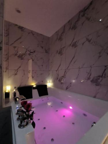 a bath tub with purple lighting in a room at LOVE ROOM - Amour Chic et Intime in Montbrison