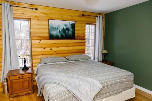 - une chambre avec un lit et un mur en bois dans l'établissement Dingle Run Lodge at Sir Sam's, à Haliburton