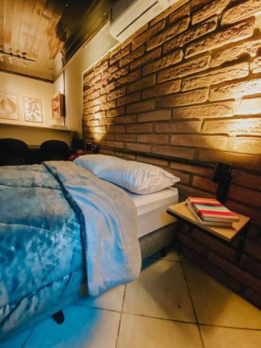 a bed in a room with a brick wall at Blue in Igrejinha