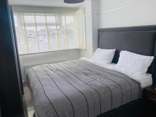 um quarto com uma cama grande e uma janela em Inviting 4-Bed House in Leeds em New Malden