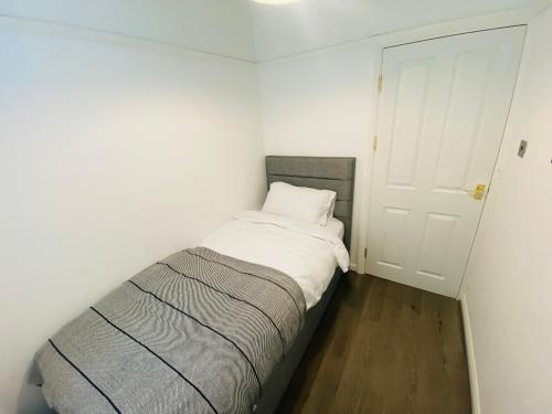 1 dormitorio pequeño con 1 cama con sábanas blancas en Inviting 4-Bed House in Leeds, en New Malden