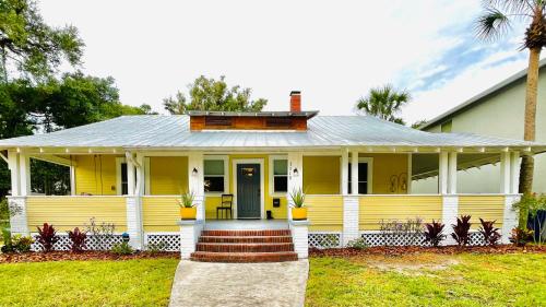 a yellow house with a porch and a house at Tampa Heights Bungalow in Tampa