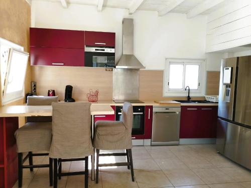 eine Küche mit roten Schränken und einem Tisch mit Stühlen in der Unterkunft Villa Tahitienne in Frontignan