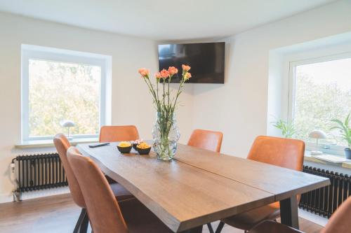 a dining room table with chairs and a vase with flowers at Tegelvillan på golfbanan in Oxie