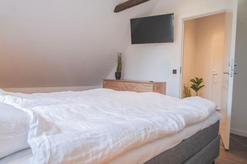 a bedroom with a white bed and a flat screen tv at Tegelvillan på golfbanan in Oxie