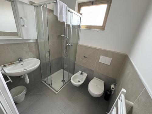 a bathroom with a toilet and a shower and a sink at Hotel Villa Augusta in Grado