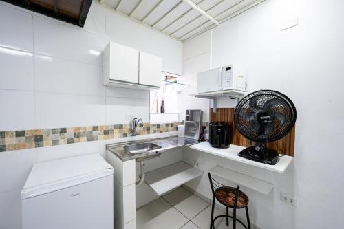 uma cozinha branca com um lavatório e uma ventoinha em 46 LOFT TRIPLO · Mini apartamento em Metrô Jabaquara e EXPO em São Paulo