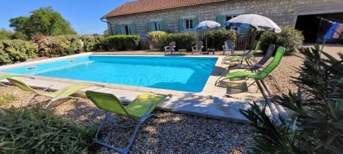 une piscine avec des chaises et un parasol dans l'établissement Les fins bois, à Gondeville