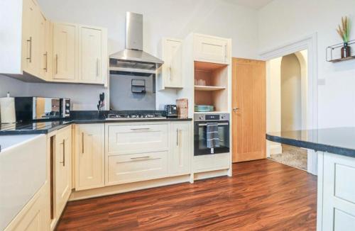 a kitchen with white cabinets and black appliances at Spacious Victorian Birkdale Apartment with Garden in Southport