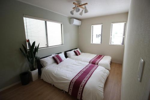 duas camas num pequeno quarto com duas janelas em HOPE VILLA Onna-son - Vacation STAY 52850 em Inbu