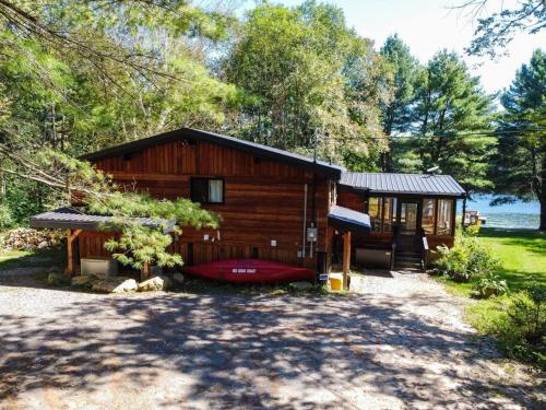 een blokhut met een rode boot ervoor bij Red Cedar Chalet on Brady Lake in Hindon Hill