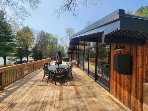 een patio met een tafel en stoelen op een houten terras bij Red Cedar Chalet on Brady Lake in Hindon Hill