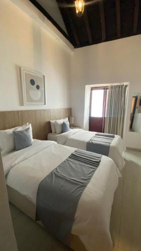 a hotel room with two beds and a window at Hotel Casa Agustina in Cartagena de Indias