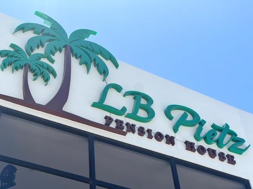 a sign on top of a building with palm trees at LB Pietz Pension House in Cordova