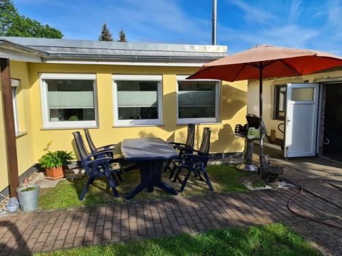eine Terrasse mit einem Tisch, Stühlen und einem Sonnenschirm in der Unterkunft Ferienhaus Muellrose am Wald in Müllrose