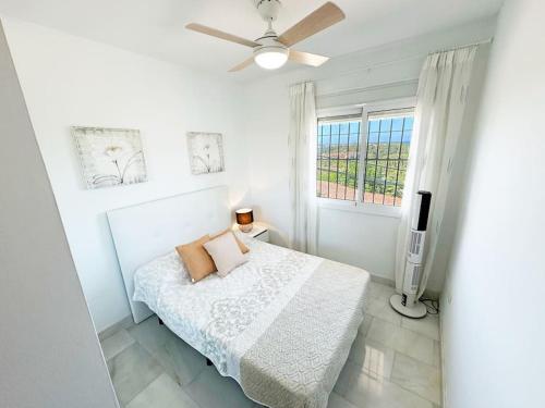 a white bedroom with a bed and a window at Apartamento luminoso con vistas al mar in Mijas Costa