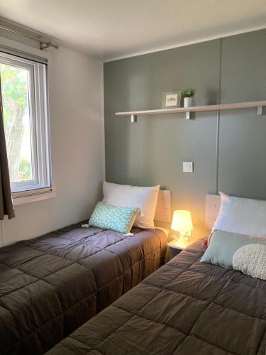 1 Schlafzimmer mit 2 Betten neben einem Fenster in der Unterkunft Mobile Home entre vignes et Rhône in Condrieu