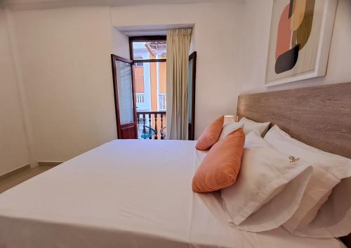 a bedroom with a bed with orange pillows on it at Hotel Casa Agustina in Cartagena de Indias