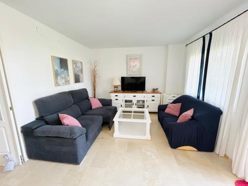 a living room with two blue couches and a tv at Adosado en Novo Atlantico Golf in Novo Sancti Petri