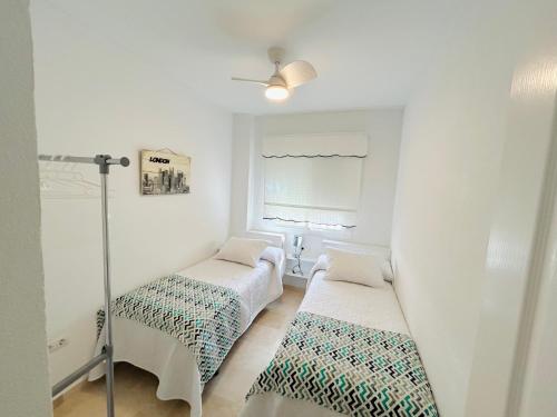 zwei Betten in einem weißen Zimmer mit Fenster in der Unterkunft Adosado en Novo Atlantico Golf in Novo Sancti Petri