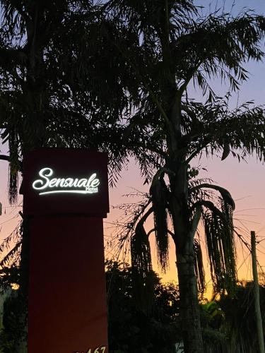 a sign in front of a tree with the sunset in the background at MOTEL SENSUALE in Valinhos