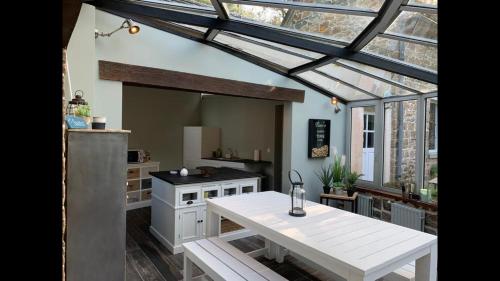 une cuisine avec une table blanche et une fenêtre dans l'établissement Les Tortues, maison bord de mer, plage à 200 m, à Plougasnou
