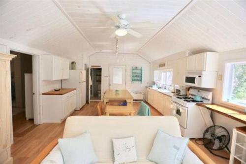 Hobie's Landing - Blissful lake side cottage - On Lake Winona في Ashland: غرفة معيشة مع أريكة بيضاء ومطبخ