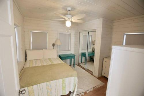 Hobie's Landing - Blissful lake side cottage - On Lake Winona في Ashland: غرفة نوم بسرير ومروحة سقف