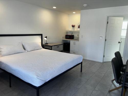 a bedroom with a white bed and a kitchen at Boulder City Inn in Boulder City