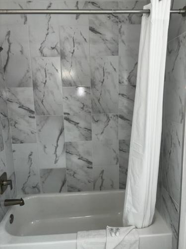 a white bathroom with a tub and a shower curtain at Boulder City Inn in Boulder City