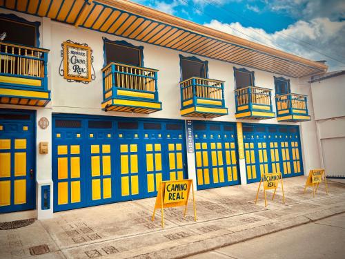 a building with blue and yellow doors and two chairs at Hospedaje Camino Real a 150 MTS del centro in Salento
