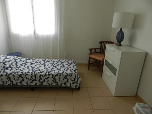 - une chambre avec un lit et une commode munie d'une lampe dans l'établissement Salines de Giens, à Hyères