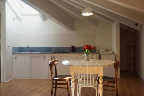 uma cozinha com uma mesa com cadeiras e um vaso de flores em Casa Pisterna em Acqui Terme