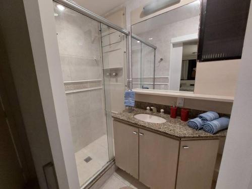 uma casa de banho com um lavatório e uma cabina de duche em vidro. em Cobertura ideal pra família toda! no Rio de Janeiro
