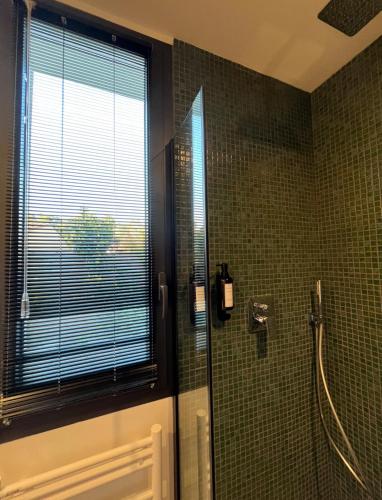 La salle de bains est pourvue d'une douche, d'une fenêtre et de carrelage vert. dans l'établissement Lodge Valbelle, maison indépendante avec jacuzzi, à Tourves
