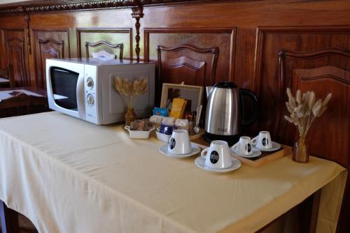 a table with a microwave and cups and saucers at Yellow Inn Aveiro in Aveiro