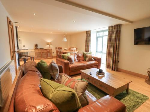 a living room with a leather couch and a table at Yew Cottage in Backbarrow