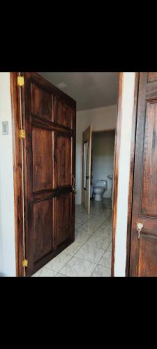 an open wooden door in a bathroom with a toilet at Casa La Frontera in Sixaola