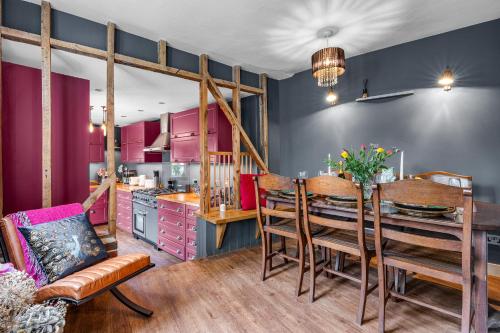 a kitchen with pink cabinets and a table and chairs at The Blue Anchor House - close to London in Hertford