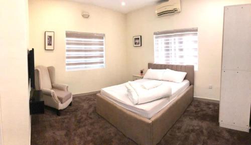 a bedroom with a bed and a chair and a window at Portland Residence in Lekki
