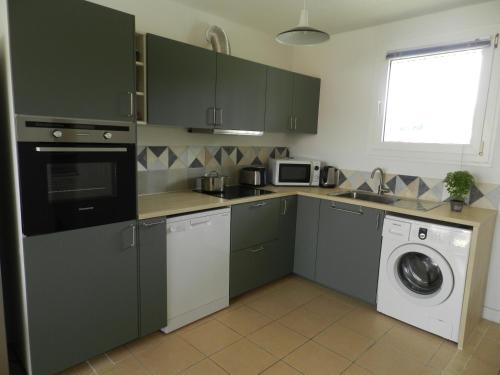 - une cuisine avec des placards verts et un lave-linge/sèche-linge dans l'établissement Salines de Giens, à Hyères