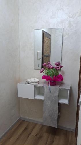a bathroom with a sink with a mirror and flowers at Verdemare in Duino