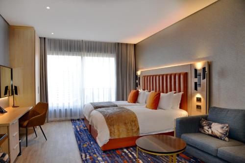 Habitación de hotel con cama grande y sofá en @Sandton Hotel en Johannesburgo